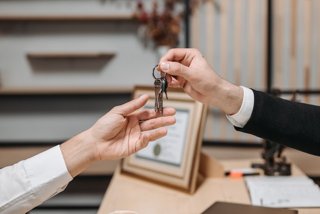 two people exchanging keys at a desk